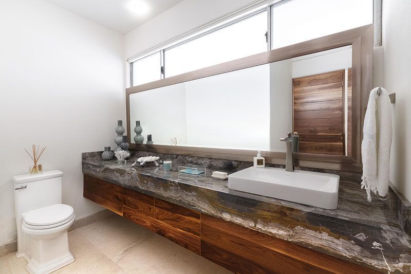 In this bathroom, a single long mirror and windows, both run the length of the vanity.