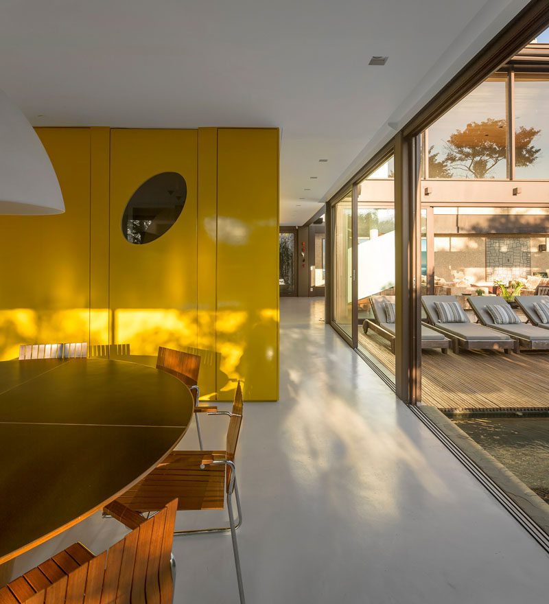 This Brazilian home has a bright yellow feature wall that hides the guest bathroom, kitchen, pantry and service stairs.