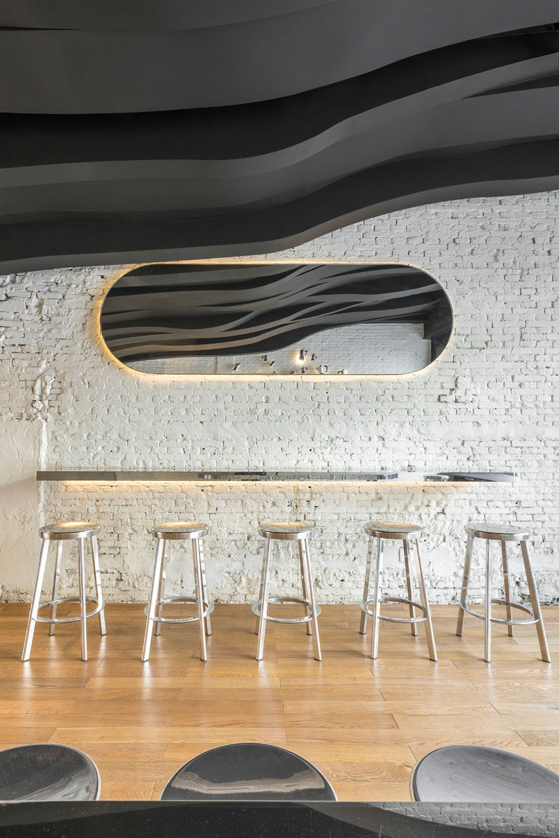 Bar seating and a mirror runs along the wall in this cafe. Both have hidden lighting.