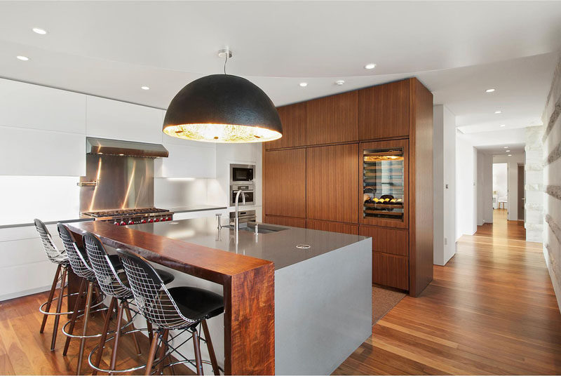 In this kitchen, there's a central island with bar seating and a large pendant light.