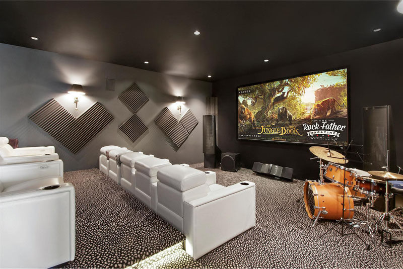 This home theater room has tiered white lounge chairs, perfect for movie viewing.