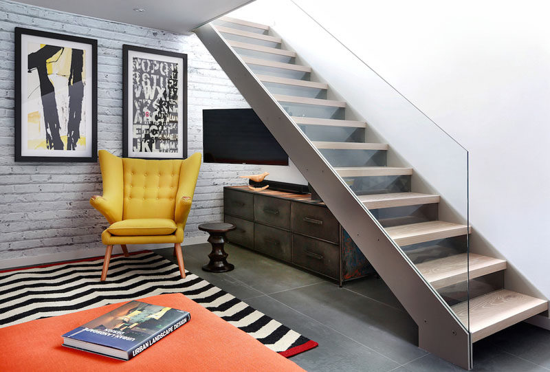 This TV/living room features an open tread glass and steel staircase.