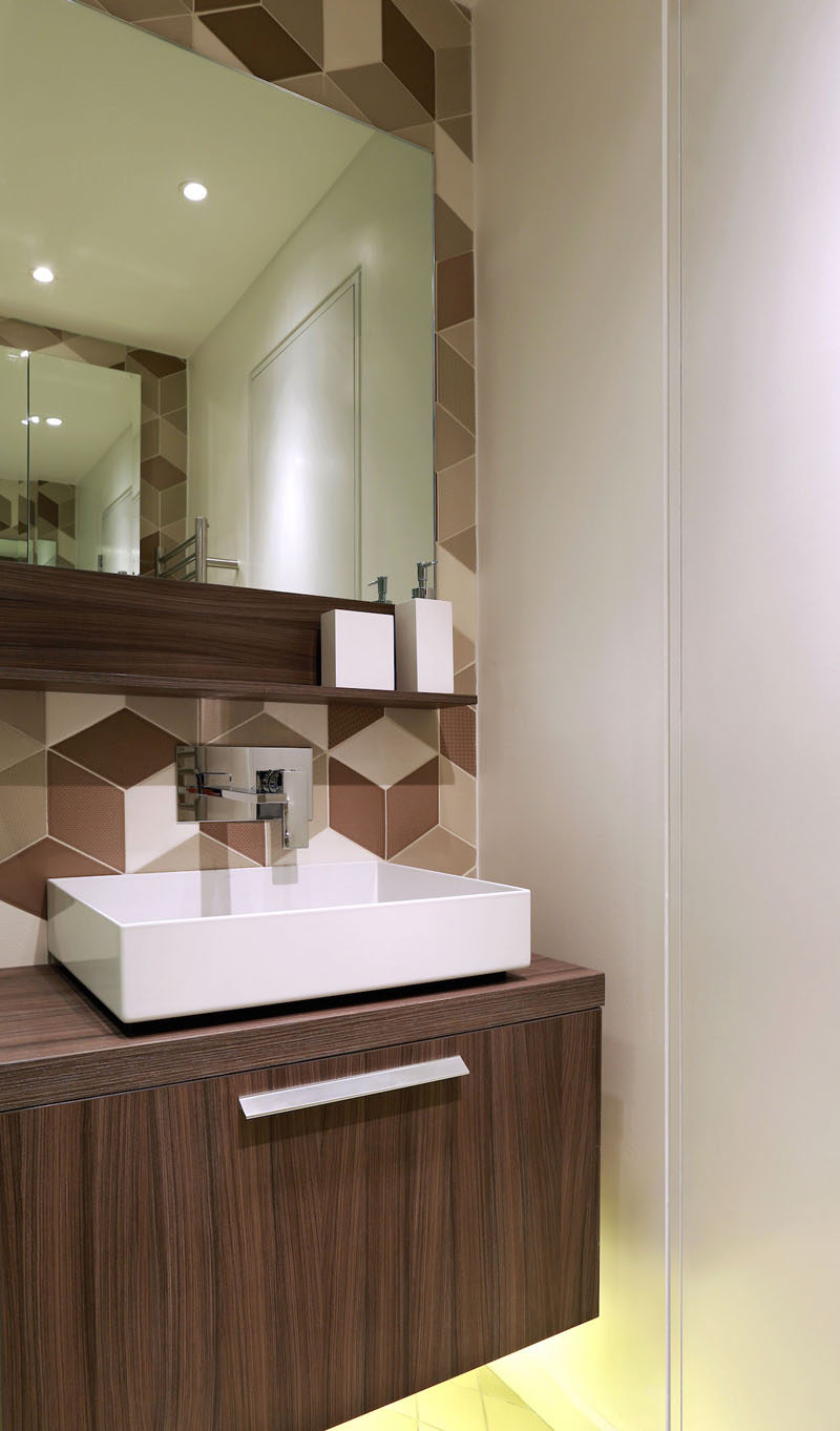 This shower room, has a huge shower and statement tiles in a diamond shape in tones of cream, cappuccino and chocolate. An LED under-lit wooden vanity unit and mirror finish the look.
