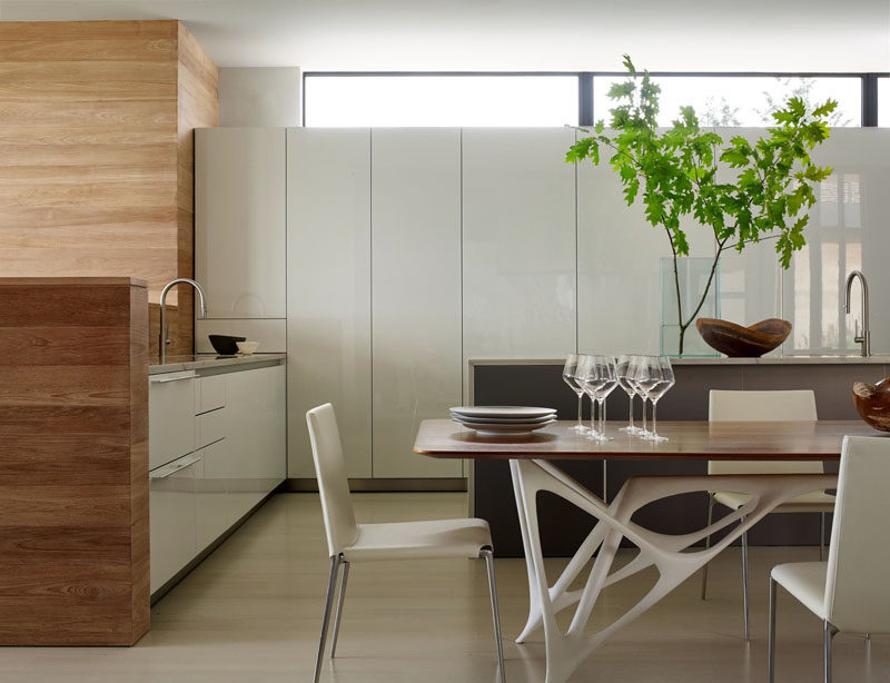 In this kitchen, white cabinets have been paired with wooden touches, like the wall and table top.