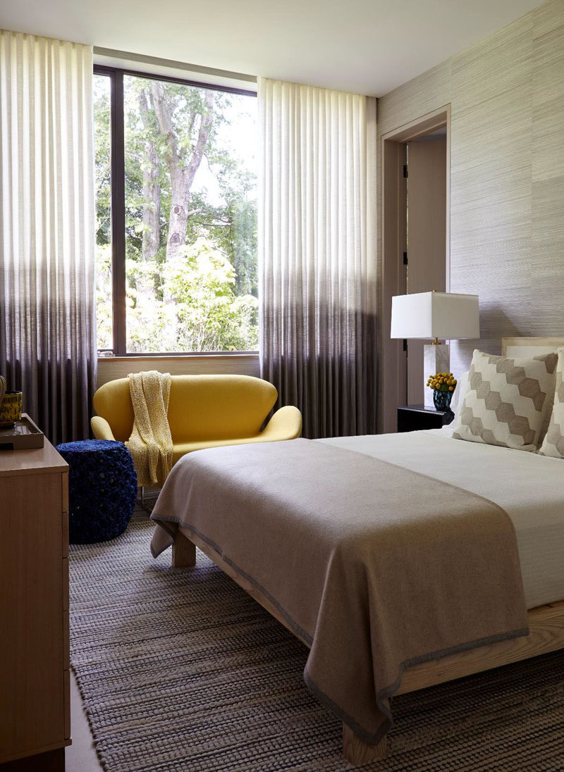 This bedroom has ombré curtains and adds a pop of colour with a small yellow sofa.