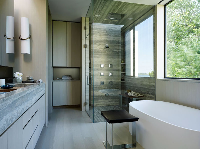 This bathroom has a glass enclosed shower with stone surround, and a large window provides lots of light.