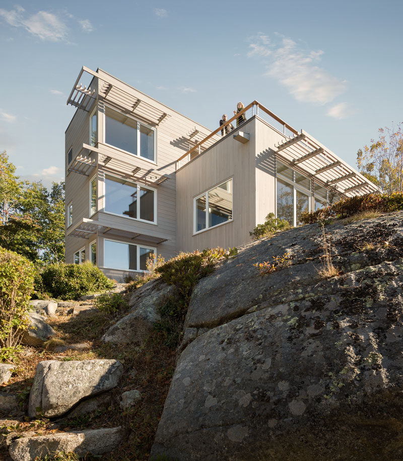 This home in Maine, USA, sits on top of granite rock and is clad in white cedar boards and zinc panels.