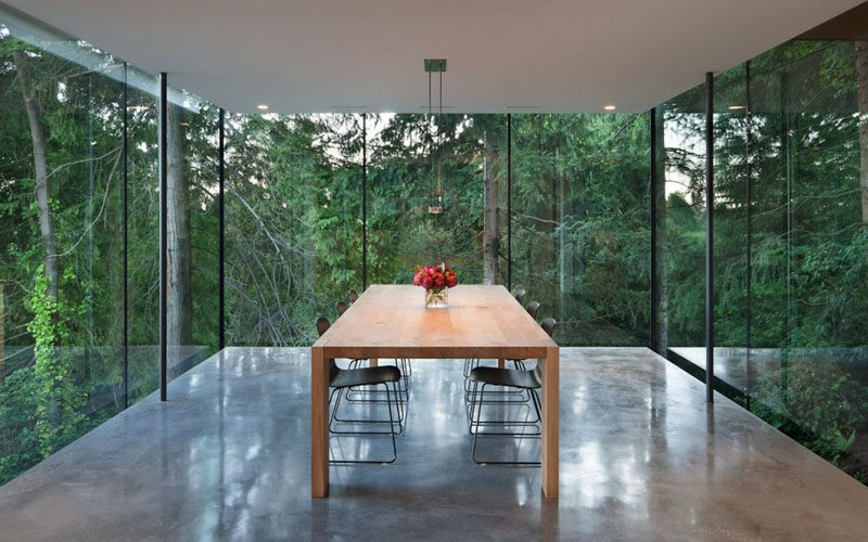 A Dining Room Surrounded By Glass Hangs Off The Side Of This House