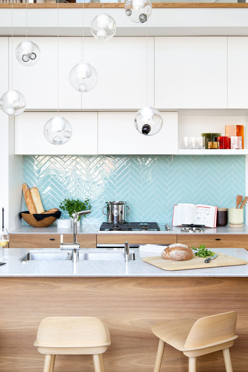 9 Inspirational Pictures Of Kitchens With Geometric Tiles // Shiny, light blue rectangular tiles laid out in a herringbone pattern create the backsplash of this Vancouver apartment.