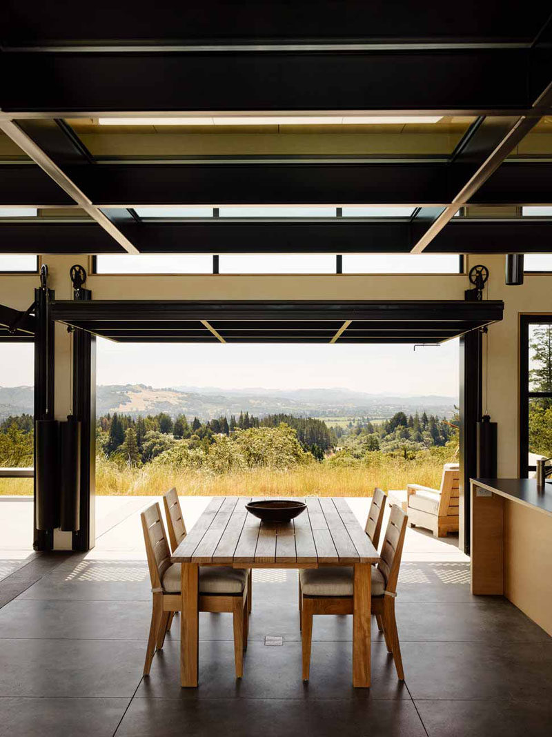 Large glass paneled doors on a pulley system open this dining room to the outdoors.