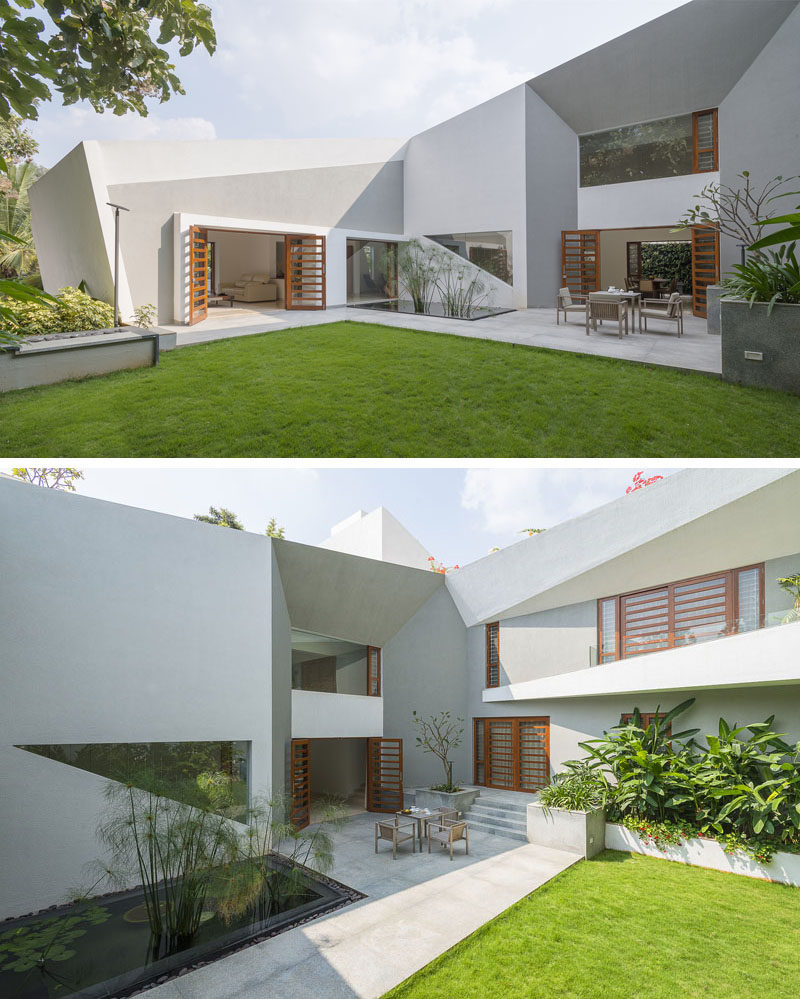 The landscaped backyard of this modern home has a large grassy area with a water feature and two patio areas that connect.