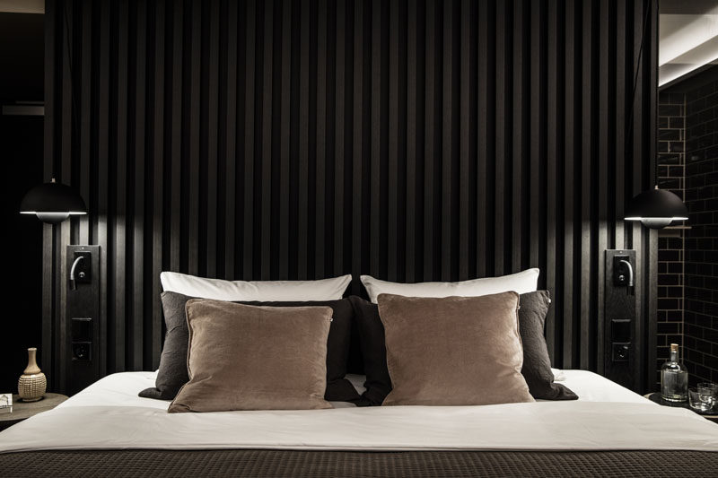 To create a dramatic and dark modern bedroom design, install a black accent wall or headboard like this one, made from black wooden slats. #DarkBedroom #BlackHeadboard #ModernBedroom #BedroomDesign