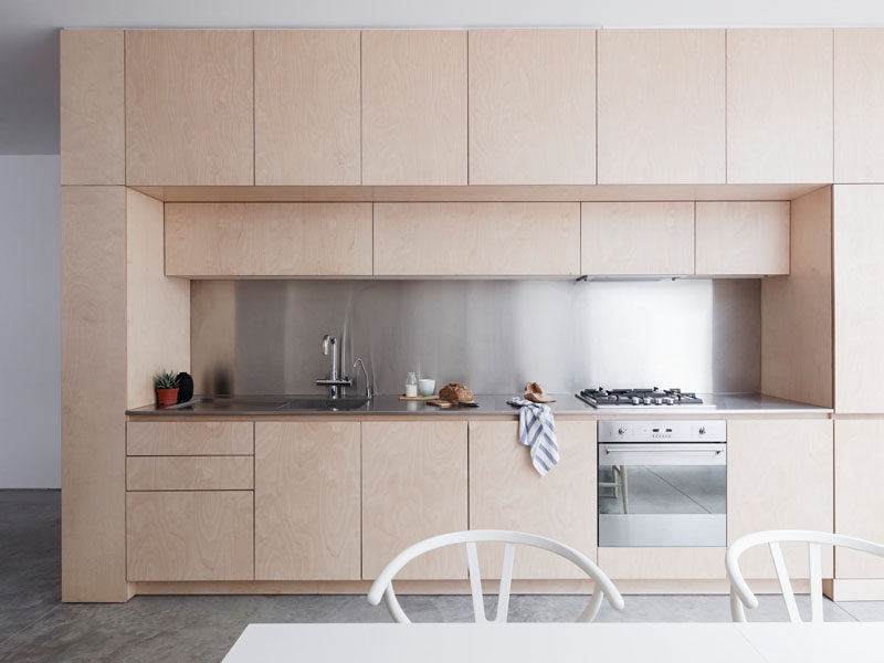 Light wood cabinets with stainless steel countertops and backsplash give this kitchen a contemporary design