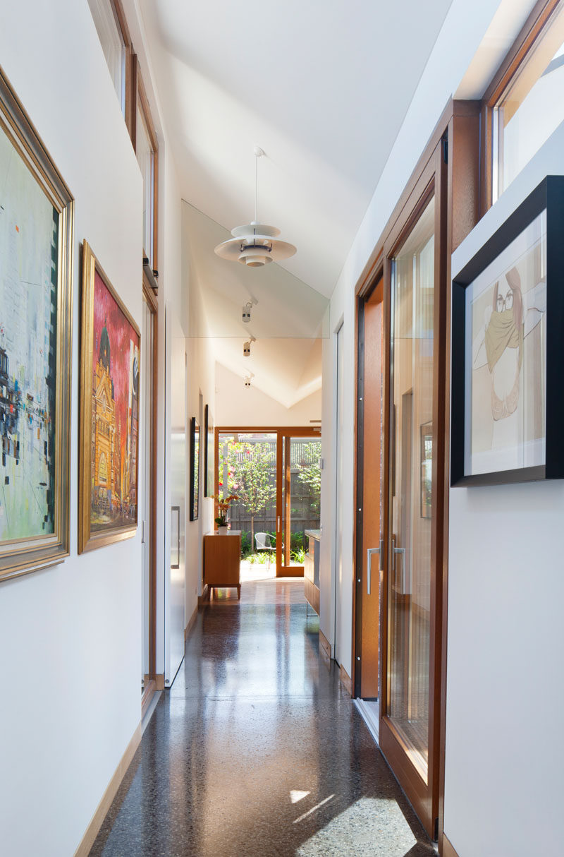 In this modern house, a long hallway lined with art leads to the various rooms or pavilions. White walls and clerestory windows help keep the home feeling airy and naturally bright.