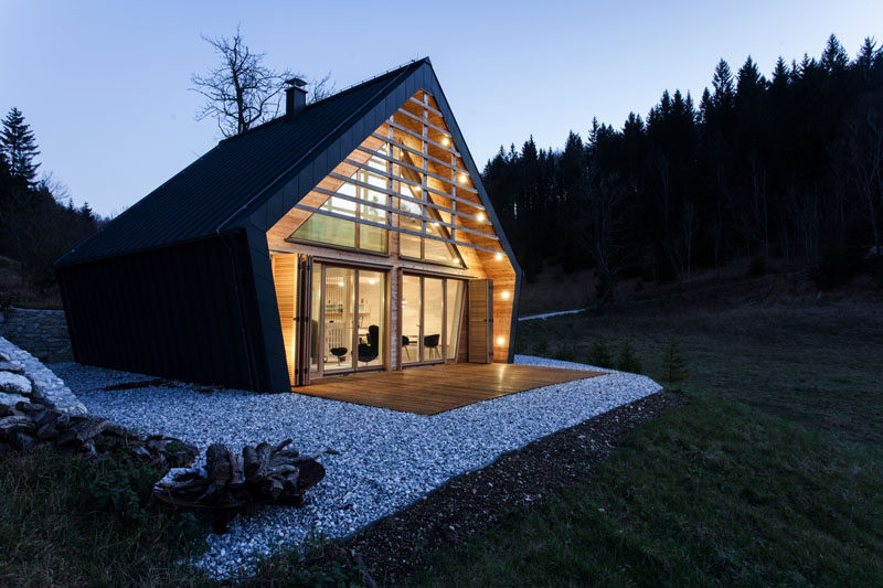 studio PIKAPLUS have designed this small two bedroom house surrounded by woods in Slovenia, that has an exterior of black metal siding and a softer light wood interior.