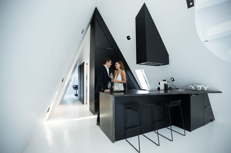 Современные матовая черная кухня была разработана, чтобы полностью соответствовать треугольной форме интерьера, с углами усугубляются сильными контрастными линиями краснодеревщика.