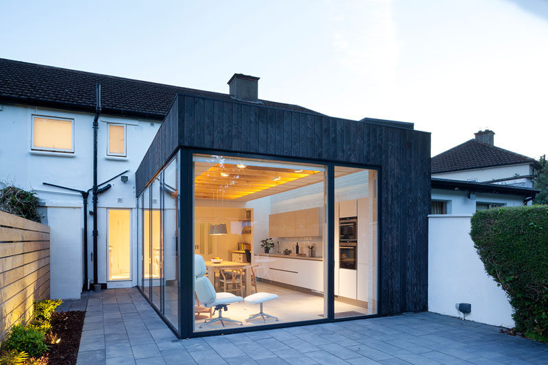 This modern house extension is covered in charred timber while the interior is a bright and airy space with a kitchen, a dining area and plenty of windows.