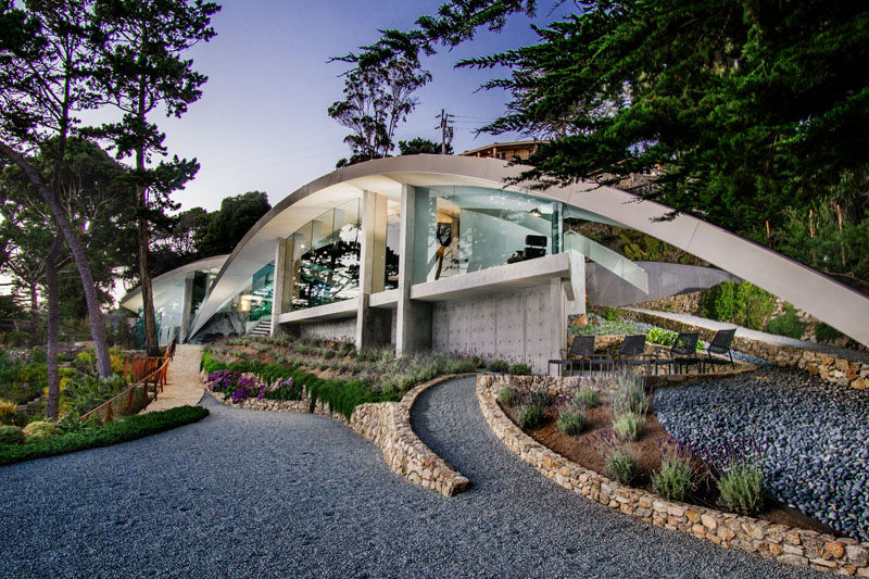 This modern house, designed by architect Wallace Cunningham, overlooks the ocean in Carmel, California, and has a sculptural appearance with glass walls and a curved stainless steel roof.