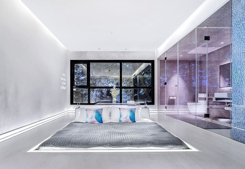 This futuristic modern hotel room features a sunken bed in the middle of the room. The bed sits flush with the floor, with only the headboard rising up from the floor.