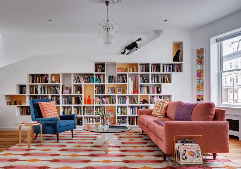 This renovated row house in Brooklyn has a custom built-in bookcase that runs the entire length of the home and it was specifically designed to allow the home owner's cats to climb it and have space to explore. #Cats #InteriorDesign #Shelving #Bookshelf #Bookcase