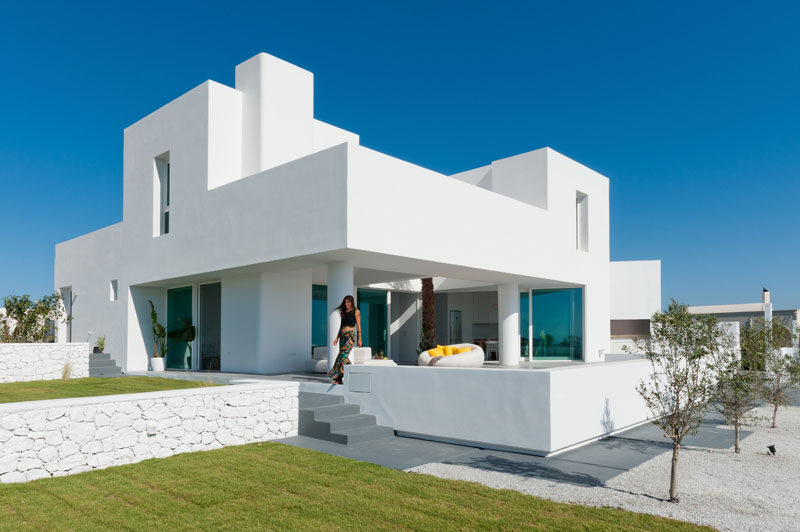 Kapsimalis Architects have design a new modern summer house in Santorini, Greece, that sits on a slightly sloped site and has views of the sea. #WhiteHouseExterior #ModernHouse #ModernArchitecture