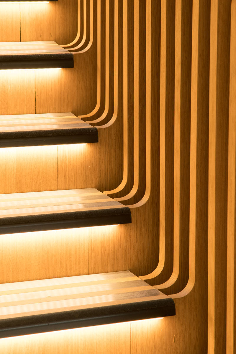 Each of the stair treads in this sculptural staircase have hidden lighting beneath them. #StairTreads #WoodStairs #StairDesign #HiddenLighting