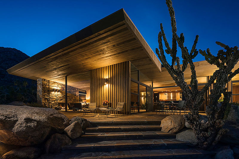 Positioned within the desert landscape, this house is an example of mid-century modern architecture. Wood features have been combined with stone walls and plenty of glass. #Wood #Stone #MidCenturyModern #House