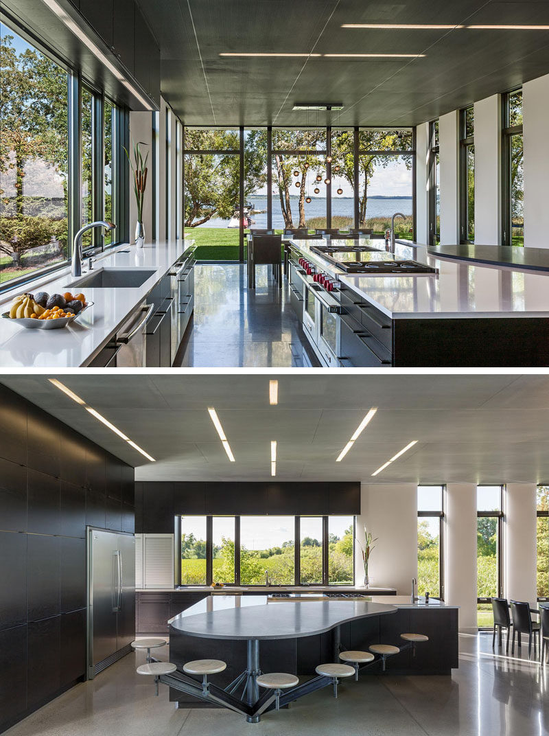 In this modern kitchen, there's concrete floors with radiant heat, and on the ceiling there's perforated blackened steel. To make sure there's enough room for the family in the kitchen, custom designed stools have been attached to the large curved island. #IndustrialModern #KitchenDesign