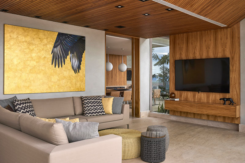 This modern living room has a wood accent wall and pillows that reflect the colors in the large artwork on the wall. #LivingRoom