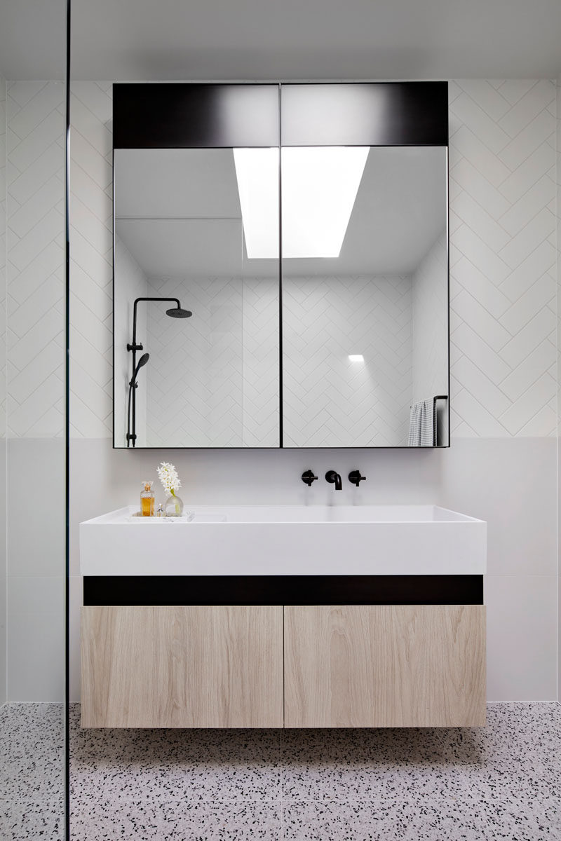 In this modern bathroom, a skylight adds natural light to the space, while the large mirror helps to reflect the light. #Bathroom #ModernBathroom #BathroomDesign
