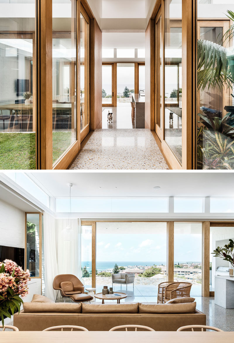 Wood-framed sliding glass doors open both the hallway and modern living room to different outdoor areas. #SlidingGlassDoors #LivingRoom #Hallway