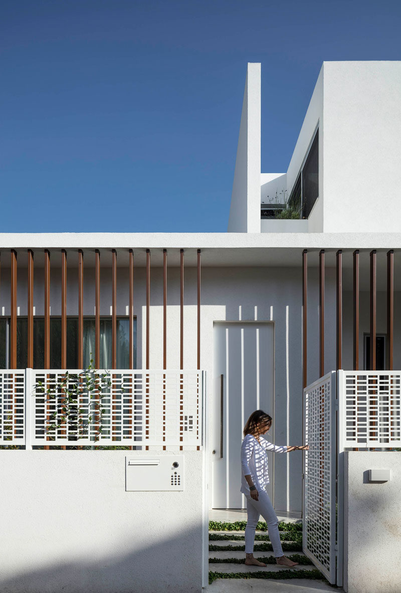 A white gate with a decorative pattern welcomes visitors to this modern house. #Gate #Architecture #ModernGate