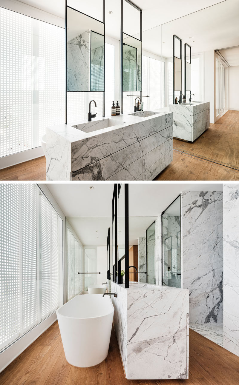 In this modern master bathroom, a double sink vanity is positioned in the center of the room, while a freestanding bathtub is located behind the vanity, and a full wall mirror makes the room feel twice as big. #ModernBathroom #BathroomDesign #EnsuiteBathroom