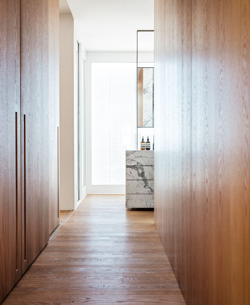 This modern bathroom has a dressing area with floor-to-ceiling wood closets. #WoodClosets #ModernClosets