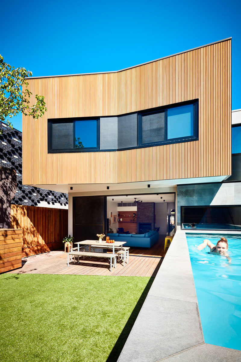 This new and modern wood clad addition opens up to the backyard, where there's a patio, a grassy area, and a swimming pool, which was required to sit above ground due to the local bedrock underneath. #ModernAddition #Wood Architecture #OutdoorSpace #SwimmingPool