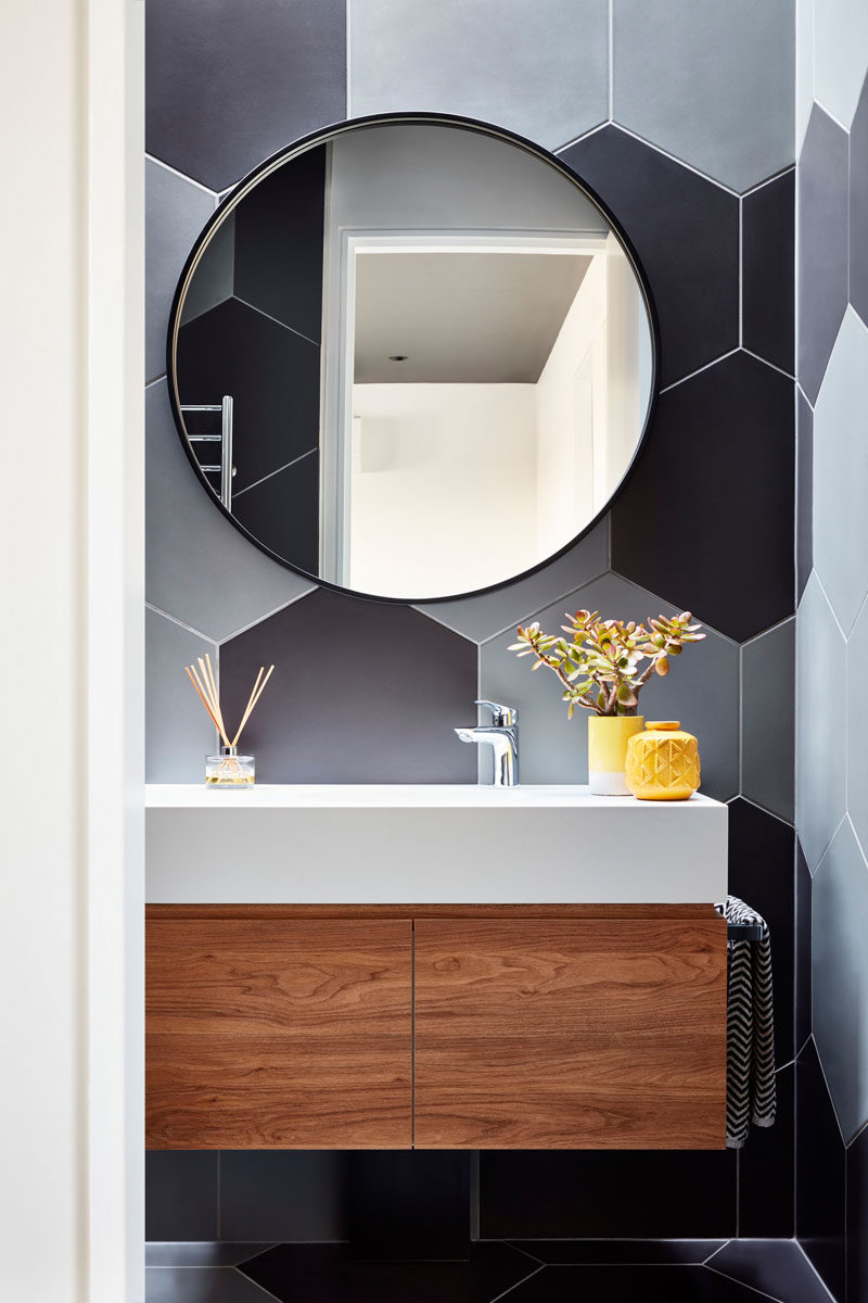 In this modern bathroom, large hexagonal tiles in a variety of grey tones cover the walls and floor. #Bathroom #ModernBathroom #HexagonalTiles