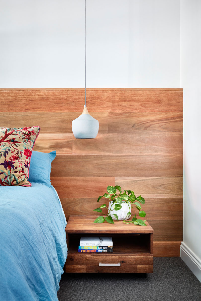 This modern master bedroom has a wood headboard, floating wood bedside tables, and modern pendant lights. #ModernBedroom #BedroomDesign