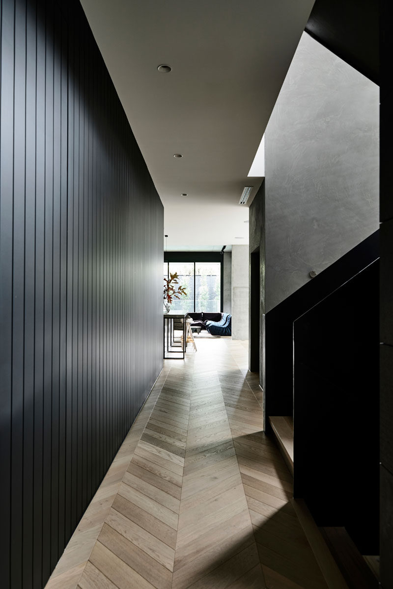 A dark wood lined hallway connects the front of this modern house to the rear, while European Oak parquetry flooring adds a natural touch to the interior. #WoodFlooring #ModernInteriorDesign #DarkHallway