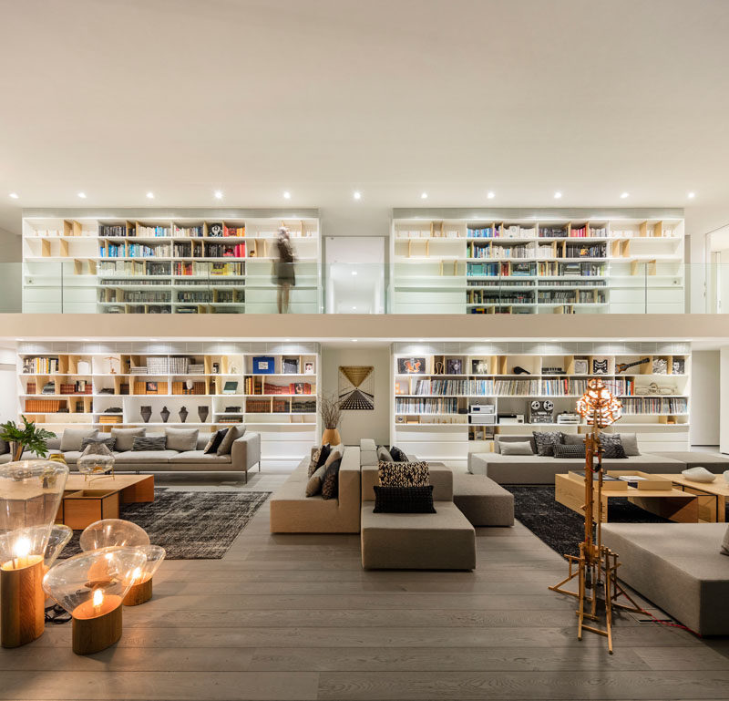 This modern living room features multiple seating areas, a double height ceiling, and a large bookshelf. #ModernLivingRoom #LivingRoom #Bookshelf #HomeLibrary