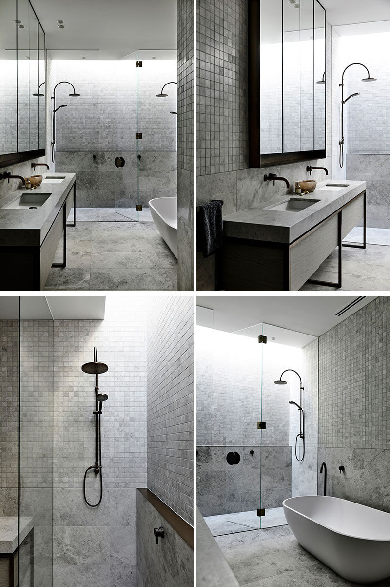 In this modern bathroom, a glass shower screen separates the double-shower from the vanity area and the freestanding bathtub. Grey tiles have been used to create a calming and spa-like environment. #ModernBathroom #BathroomDesign #DoubleShower