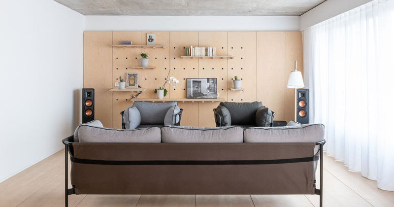 This modern apartment uses minimalist wood pegboard walls in the living room and master bedroom to create shelving for flexible displays and storage. #PegboardWall #Pegboard #InteriorDesign #Shelving