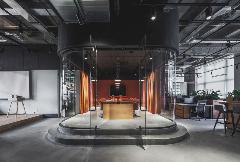 This modern office in Russia features a meeting room that's slightly raised and enclosed in a room with curved glass walls. #ModernOfficeDesign #OfficeInterior