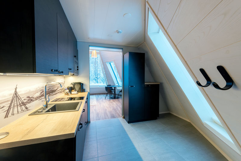 This minimalist kitchen features black cabinetry, an artistic backsplash, and a wood countertop. #Kitchen #BlackKitchen #KitchenDesign