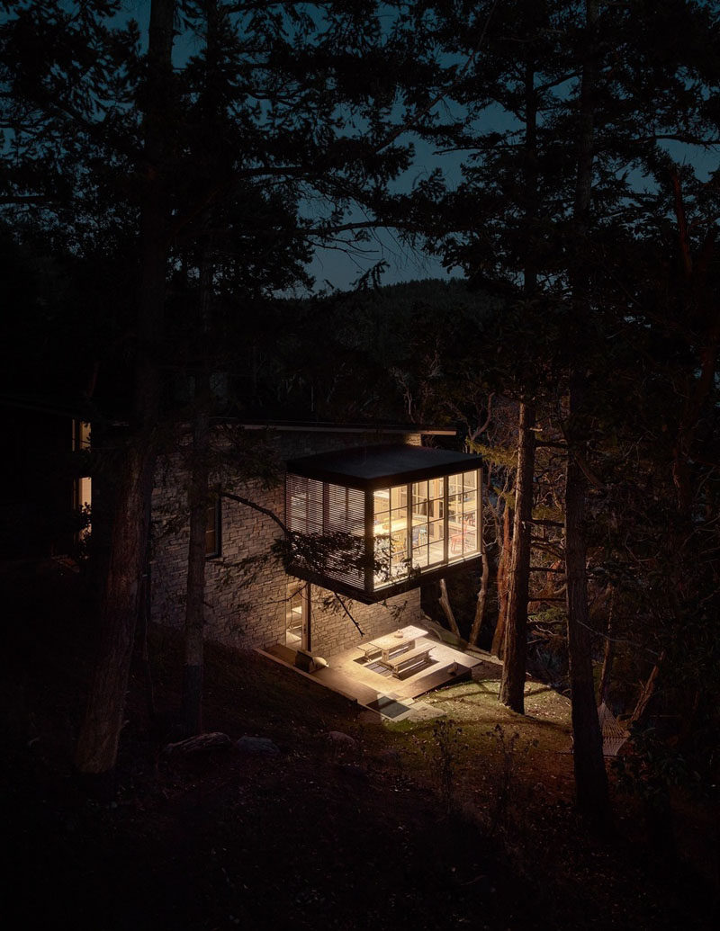 This guest house features a dining room that was conceived as a three-sided glass object floating in a forest of trees. Below the dining room, there's an alfresco dining area that's lit from lights underneath the cantilevered dining room above. #Cantilever #Architecture #DiningRoom