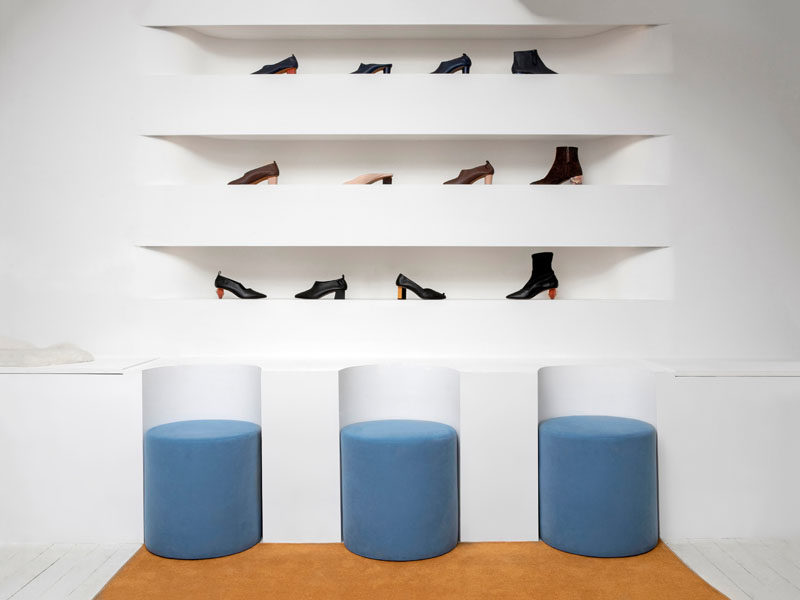 As part of the design of this modern showroom, the white benches around the edges of the interior have curved sections cut out to house the soft, dusty blue seats. #Seating #Showroom #RetailDesign
