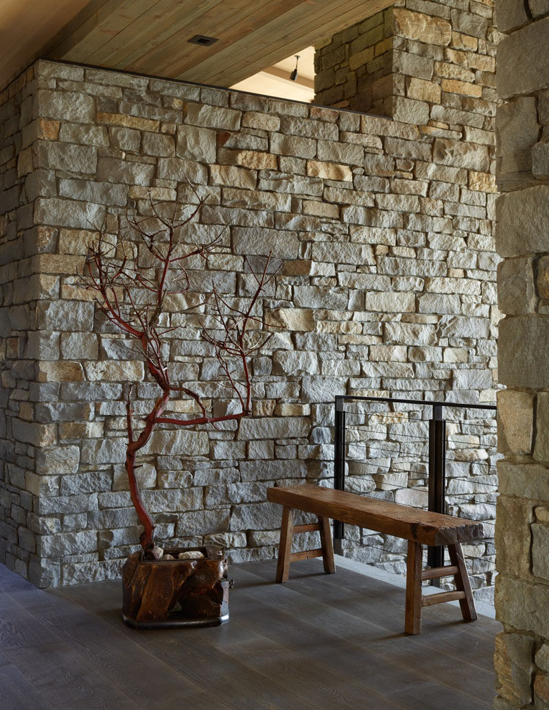 A pair of thick stone walls in this house separates the main level into public and private realms and flanks a central stone staircase. #StoneWall #Entryway