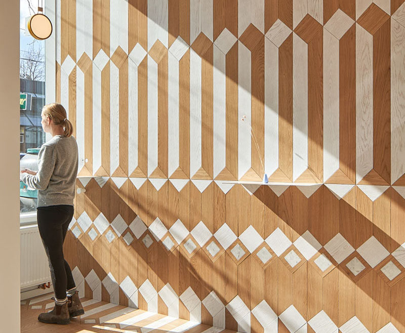 This modern coffee shop has a fun and bright geometric pattern on the walls, floor, and ceiling, made from white-washed wood and natural wood. #CoffeeShop #Cafe #InteriorDesign #RetailDesign