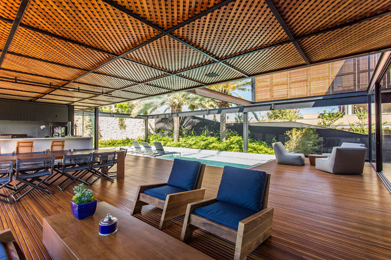 This modern house has a covered entertaining area with an outdoor kitchen, dining area, and lounge. #ModernHouse #WoodCeiling #EntertainingArea #OutdoorSpace