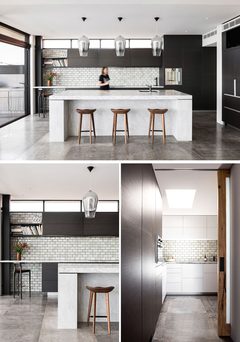In this modern kitchen, subway tiles complement the light colored countertop and large island, while a pantry is tucked away off to the side through a pocket door. #ModernKitchen #DarkWoodCabinets #KitchenIsland #Pantry