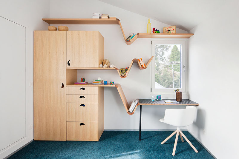 This modern kids bedroom features a custom designed wood desk that transition into benches and shelves. Floating shelving on the walls provides much need additional storage. #Shelving #KidsFurniture #FurnitureDesign